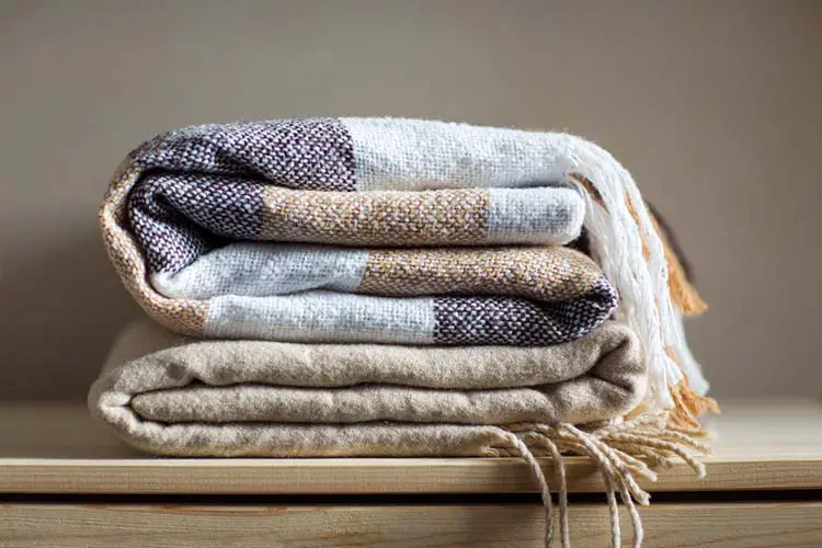 home textile. stack of beige wool blankets on a wooden shelf.