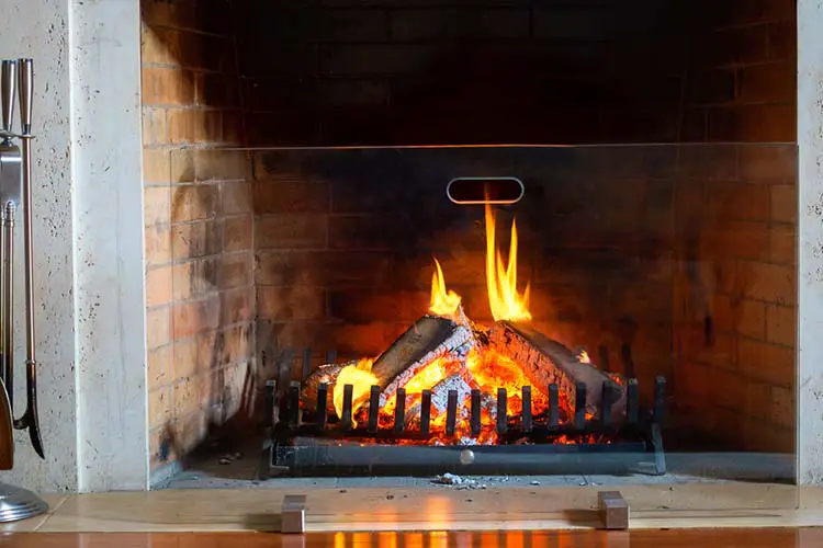 Wood burning in a cozy fireplace at home in interior. Fireplace as a piece of furniture.