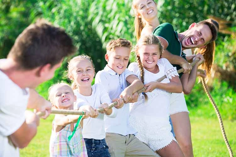 Group of laughing young people with kids having fun together playing outdoors 