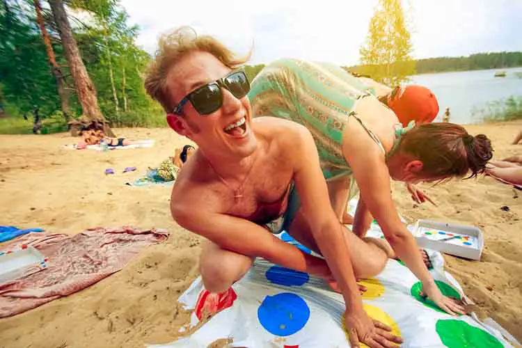 Happy hipsters playing Twister on the beach