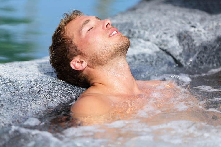 Wellness Spa - man relaxing in hot tub whirlpool jacuzzi outdoor at luxury resort spa