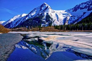 Partially Frozen Lake with Mountain Range Reflected in the Great Alaskan Wilderness