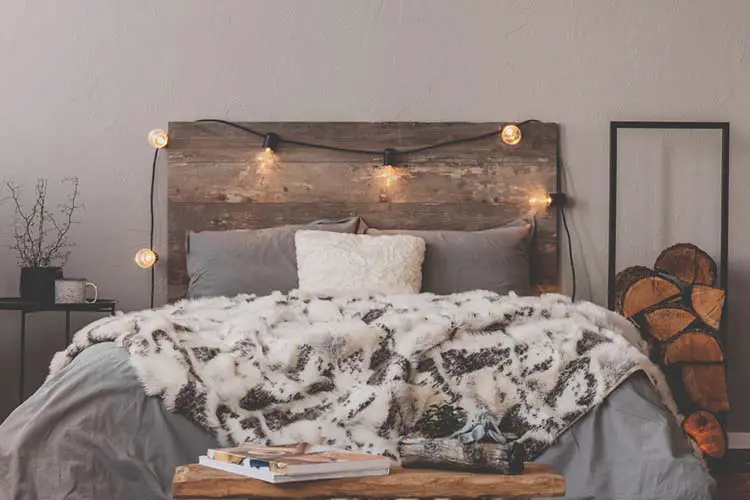 Warm duvet on comfortable bed with rustic headboard with lights